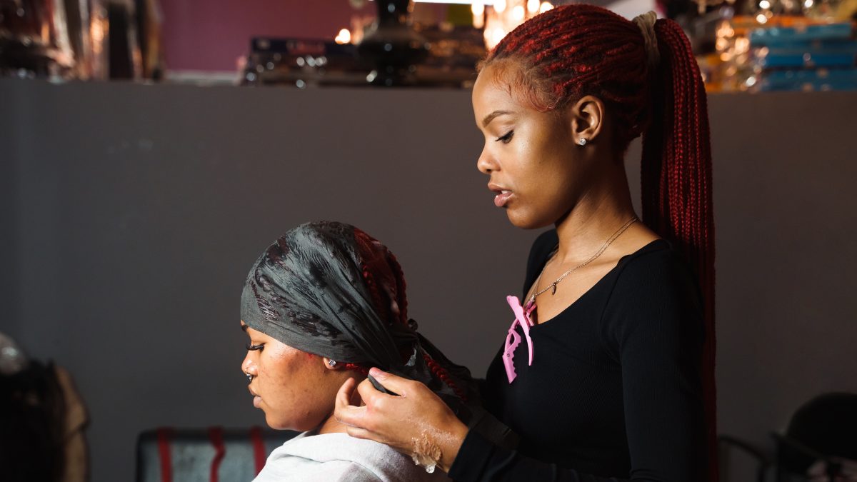 A black beauty pro styles a client's hair in her salon.